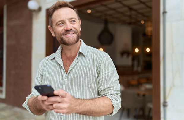 Handsome middle-aged man reviewing his Selective insurance policy on his smartphone.